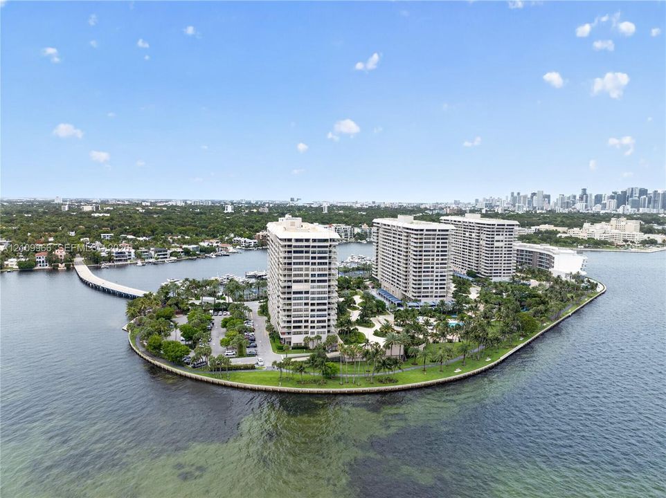Waterfront high-rise complex on a private island, featuring landscaped grounds, surface parking, and dockage