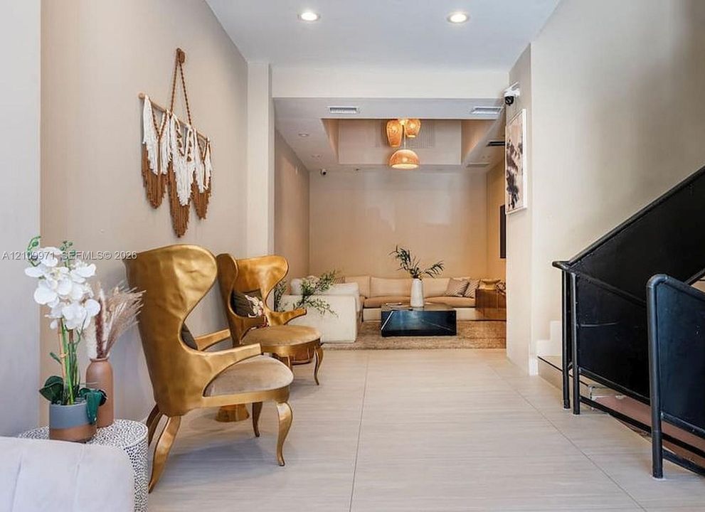 Neutral wall tones, large-format tile flooring, recessed ceiling lighting, multi-tiered pendant lighting, and an industrial-style staircase featuring black metal railing