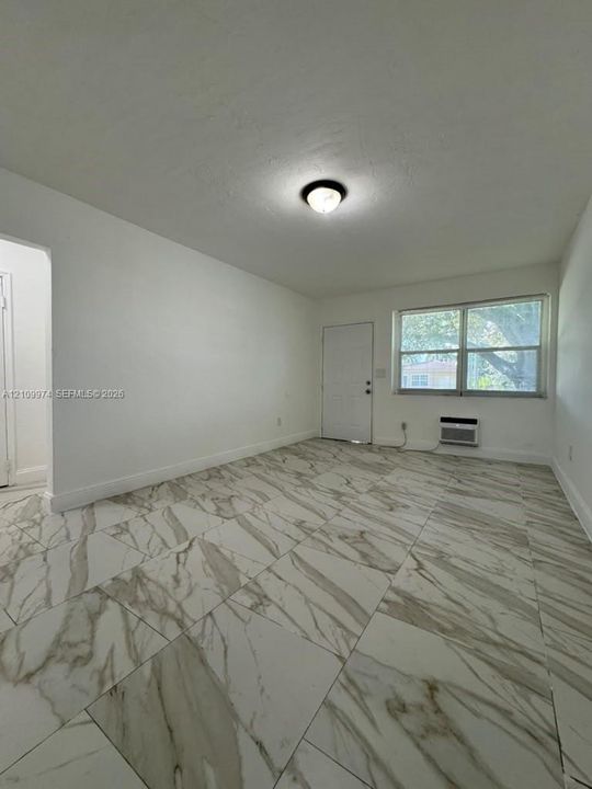 Large-format tile flooring with veined detailing, neutral interior paint, and a multi-pane window