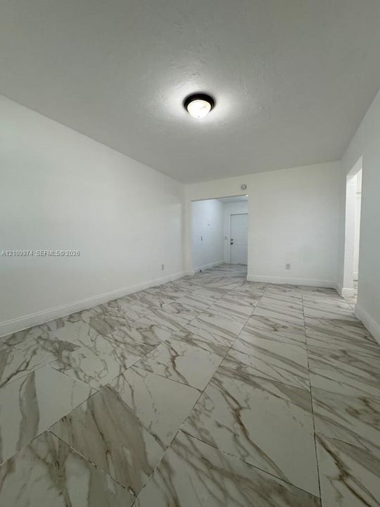 Neutral interior space featuring large-format patterned tile flooring and a flush-mount ceiling light fixture