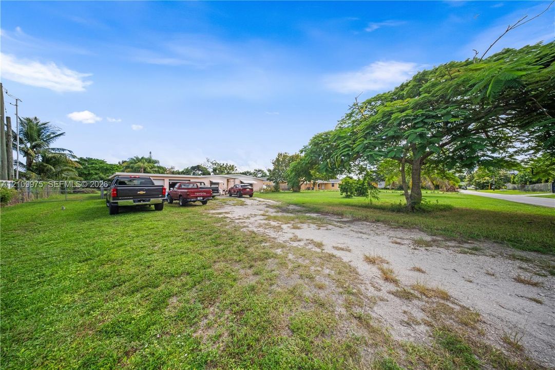 Expansive lot featuring a gravel driveway, mature trees, and open green space