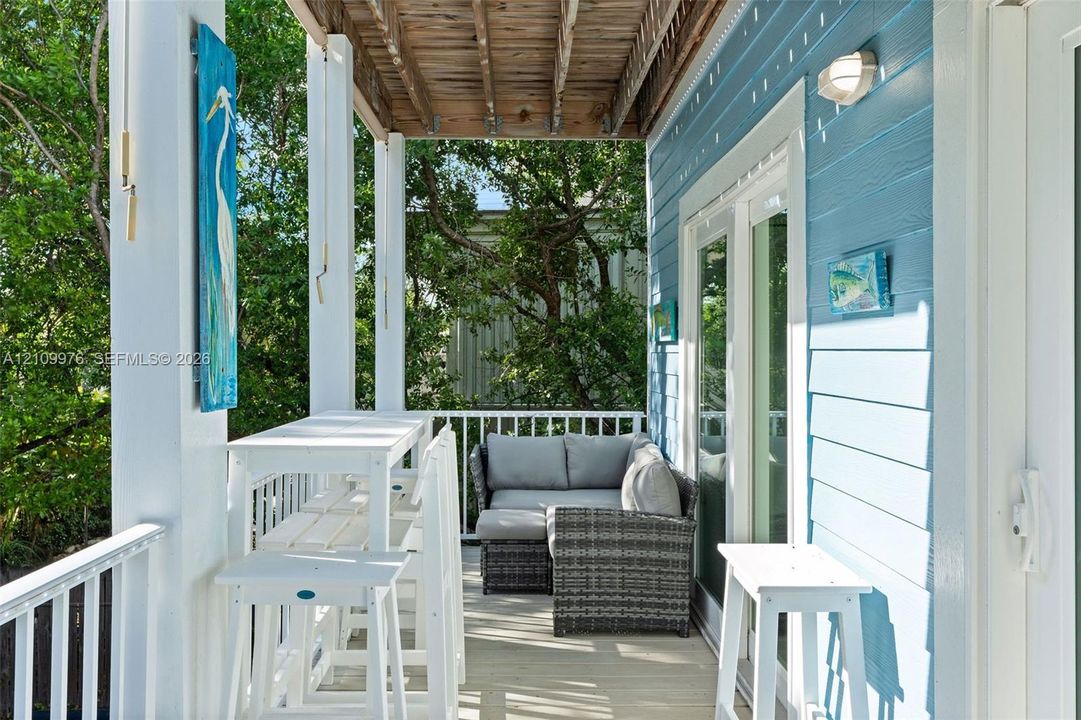 Covered porch featuring lap siding, white structural columns, wood-plank flooring, and double glass doors