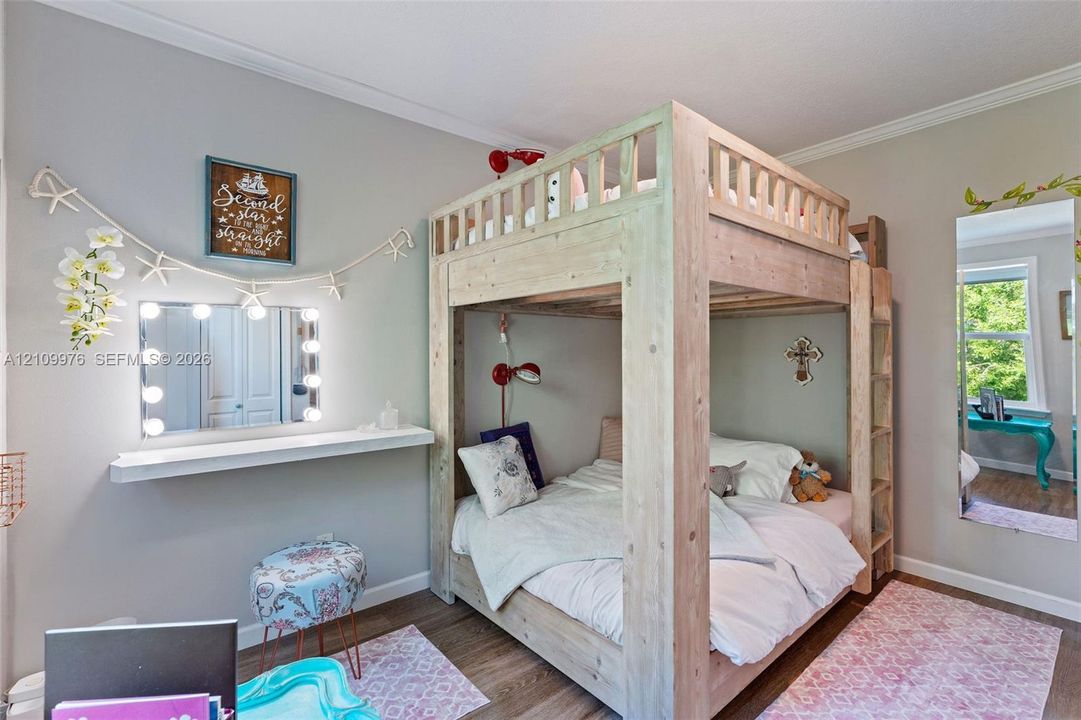 Room featuring light-toned interior paint, wood-finish flooring, and a window with natural exterior scenery