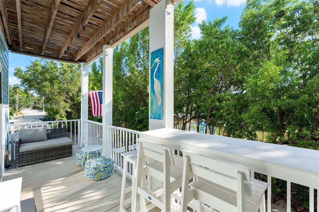 Covered porch featuring wood-finish decking, white baluster railings, and a built-in elevated counter