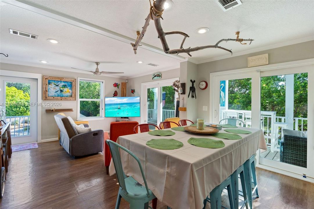 Open-concept floor plan featuring wood-finish flooring, recessed lighting, ceiling fan, and sliding glass doors opening to an exterior deck
