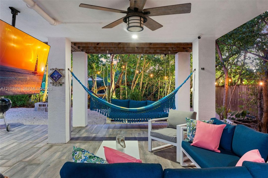 Covered outdoor patio featuring wood-finish flooring, a ceiling fan with integrated lighting, and substantial structural pillars