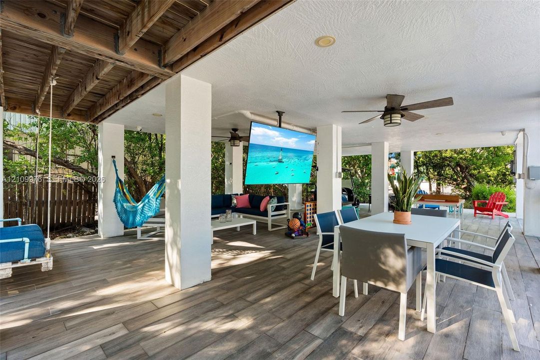Covered patio featuring wood-finish flooring, recessed lighting, ceiling fans, and a ceiling-mounted television