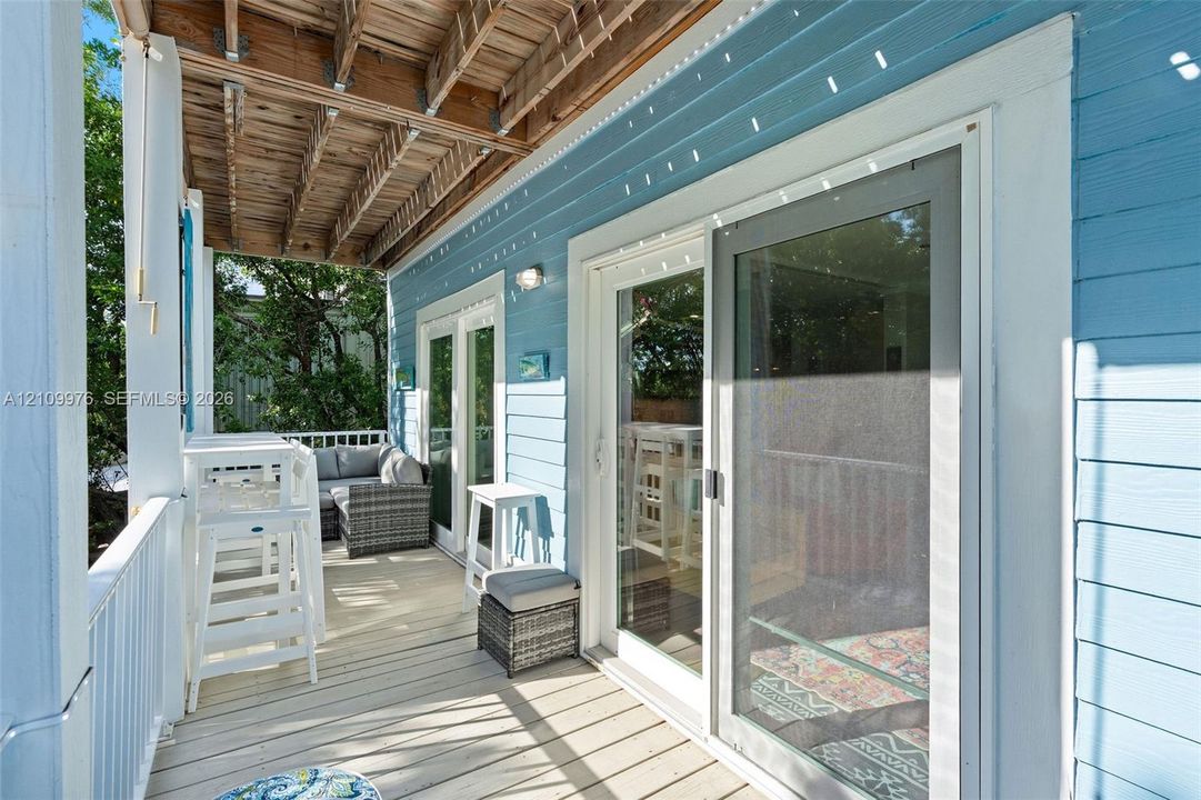 Covered outdoor deck featuring light-toned wood decking, horizontal lap siding, and sliding glass doors