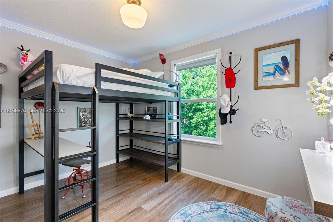 Wood-finish flooring, crown molding with integrated LED perimeter lighting, and a single-hung window