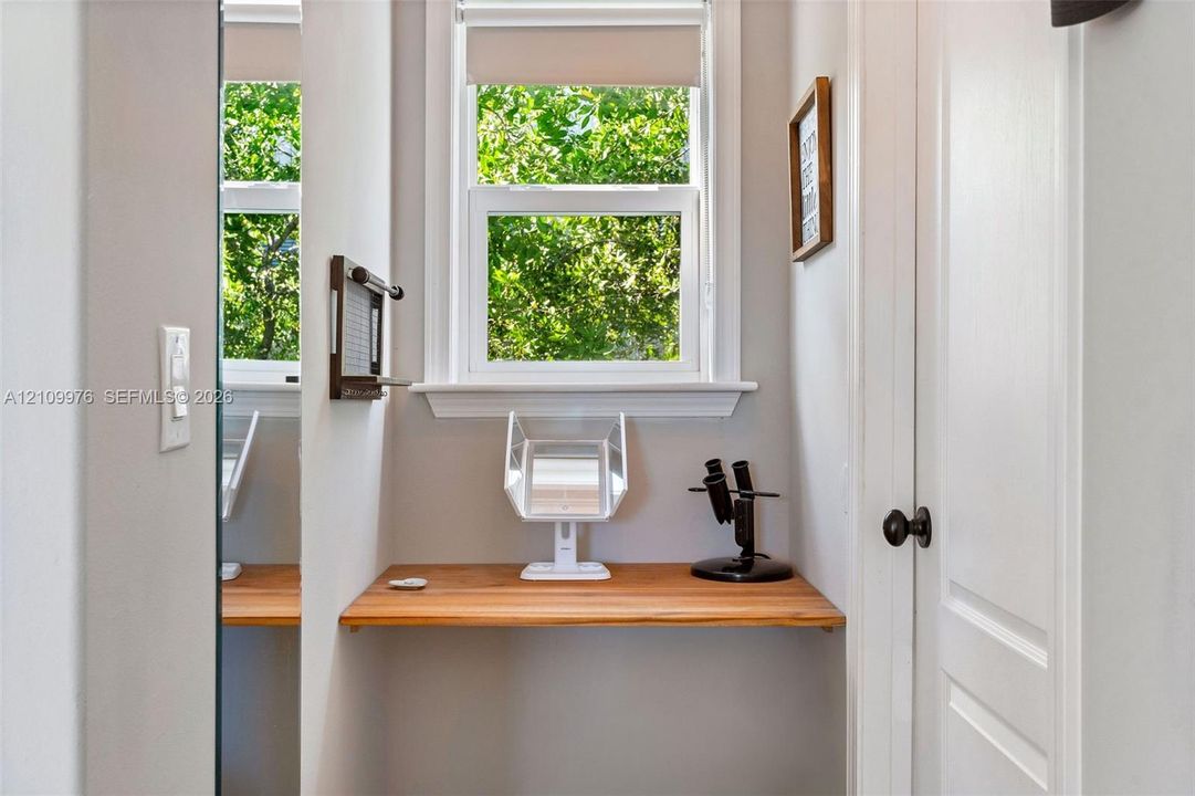 Built-in wooden wall-mounted desk, dual-pane window with white trim, and interior panel door with black hardware