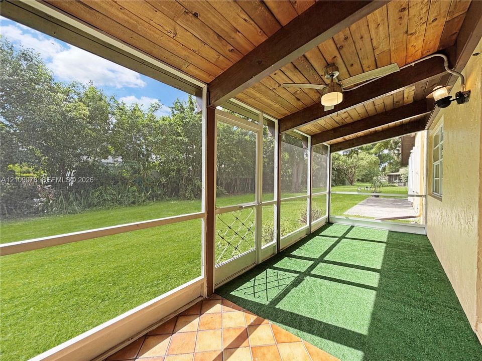 Screened lanai featuring a wood-plank ceiling, ceiling fan, tile flooring, and integrated exterior lighting