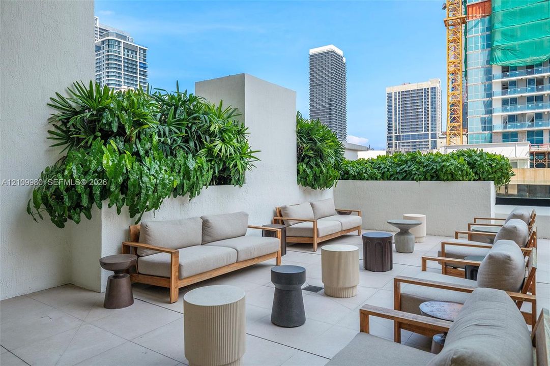 Expansive outdoor terrace featuring light-toned paved flooring and built-in masonry planters with integrated greenery