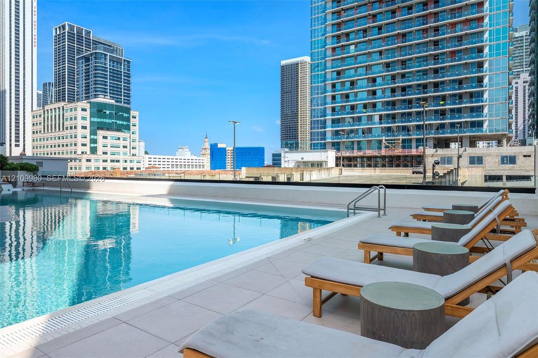 Rooftop swimming pool with a glass-paneled perimeter and light-toned tile decking