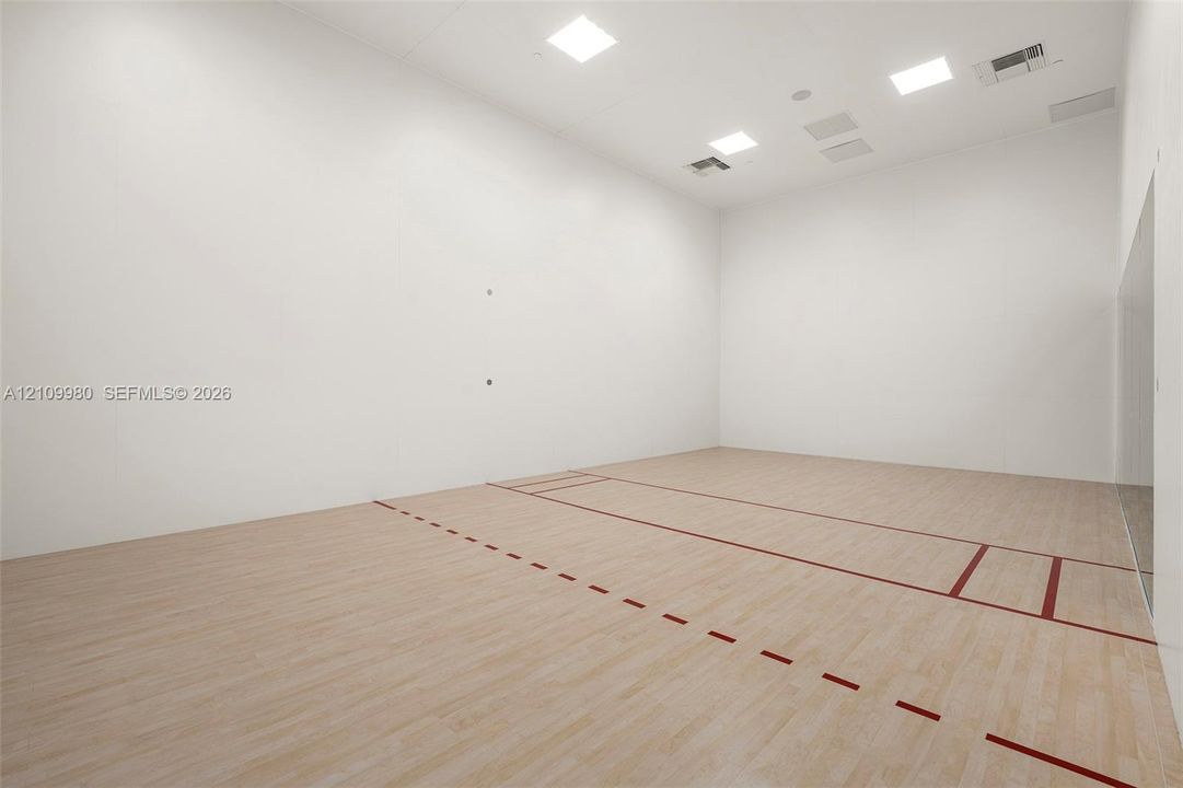 Recreation court featuring light wood-finish flooring, high ceilings, recessed lighting, and white smooth-finish walls with court-marked boundaries