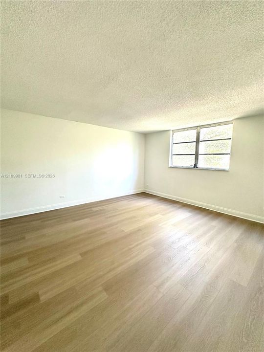 Interior space featuring wood-finish flooring, a multi-pane window, and neutral wall tones