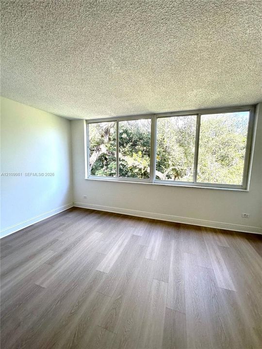 Room featuring large sliding windows, wood-finish flooring, and a textured ceiling