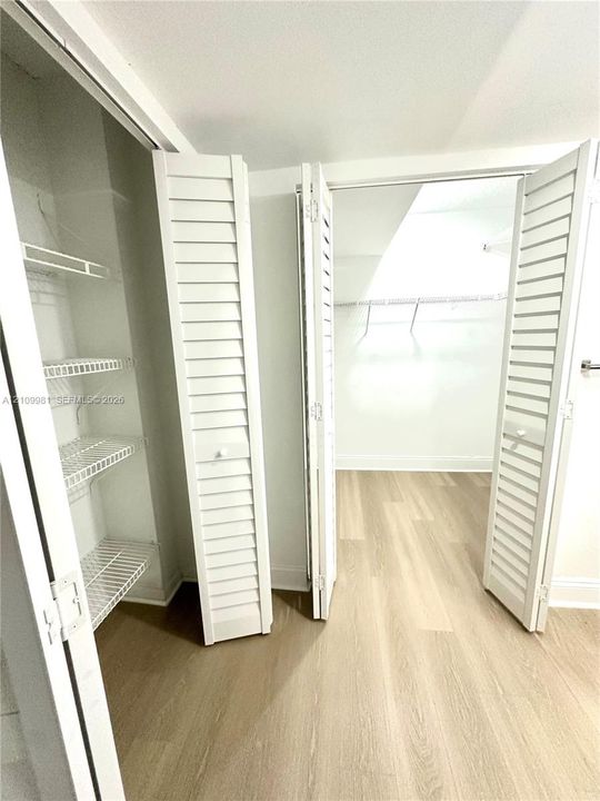 Storage area featuring louvered bi-fold doors, white wire shelving, and wood-finish flooring