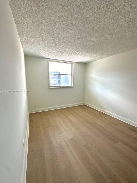 Room featuring light-toned wood-finish flooring, neutral walls, and a single-pane window