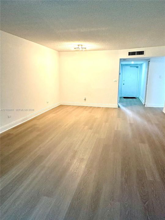 Open-concept area featuring neutral wall paint, wood-finish flooring, and recessed ceiling-mounted light fixture