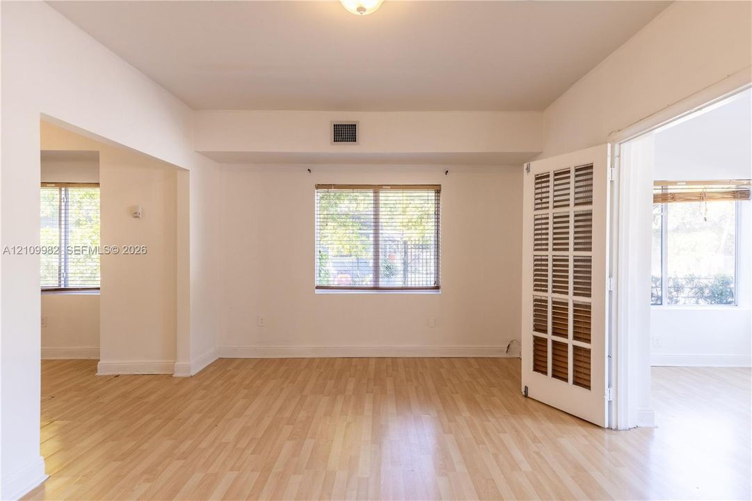 Interior space featuring wood-finish flooring, white walls, and multiple windows with blinds