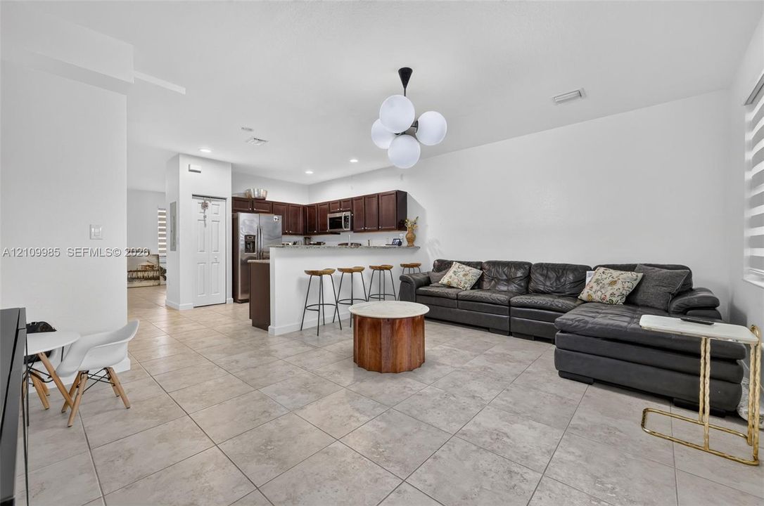 Kitchen featuring dark wood cabinetry, stainless steel appliances, and a breakfast bar, illuminated by a multi-globe pendant light fixture over tile flooring