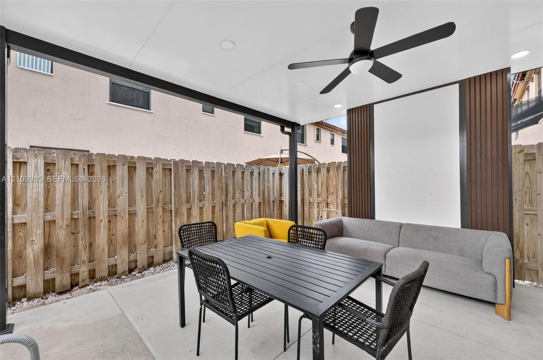 Covered patio featuring recessed lighting, a matte black ceiling fan, and decorative vertical wall slats