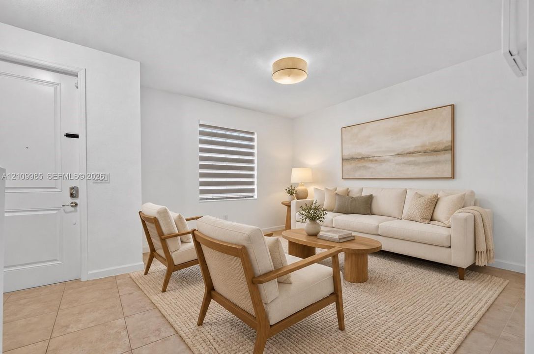 Neutral-toned interior featuring ceramic tile flooring, a multi-panel door with brushed nickel hardware, a flush-mount circular light fixture, and a window fitted with horizontal blinds