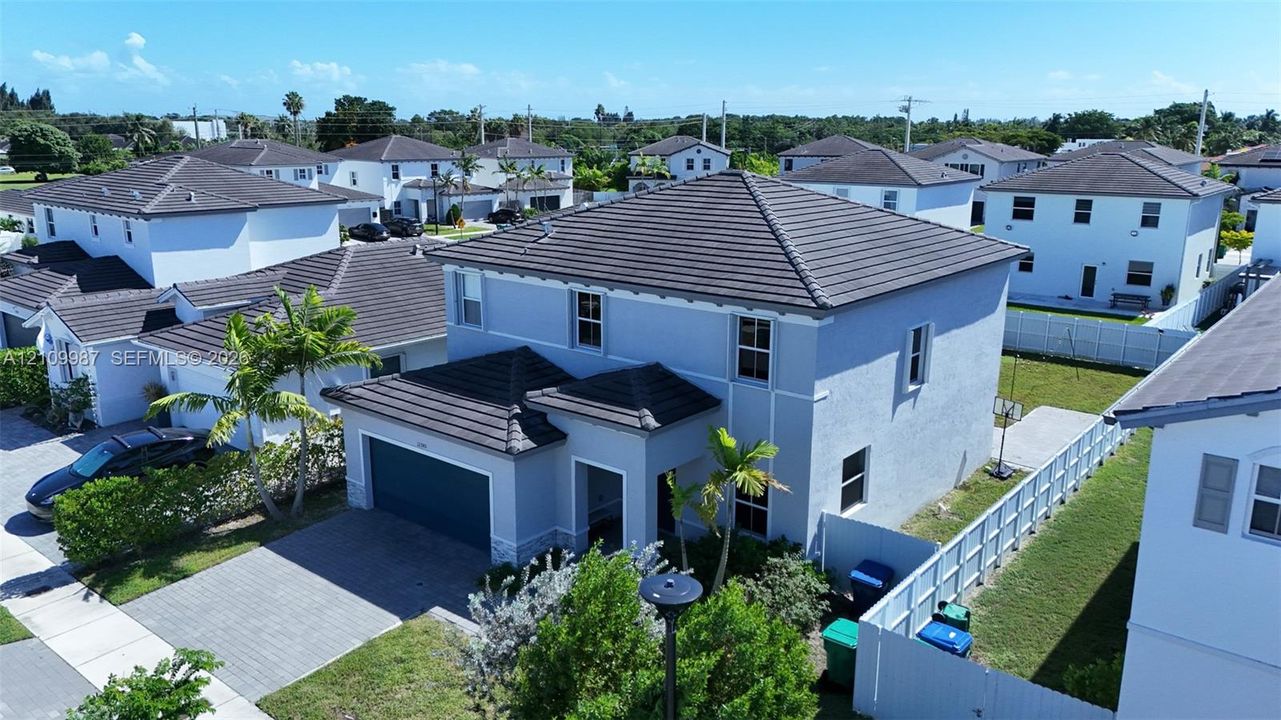 Aerial perspective of a two-story residence featuring a shingled roof, stucco exterior, and an attached two-car garage