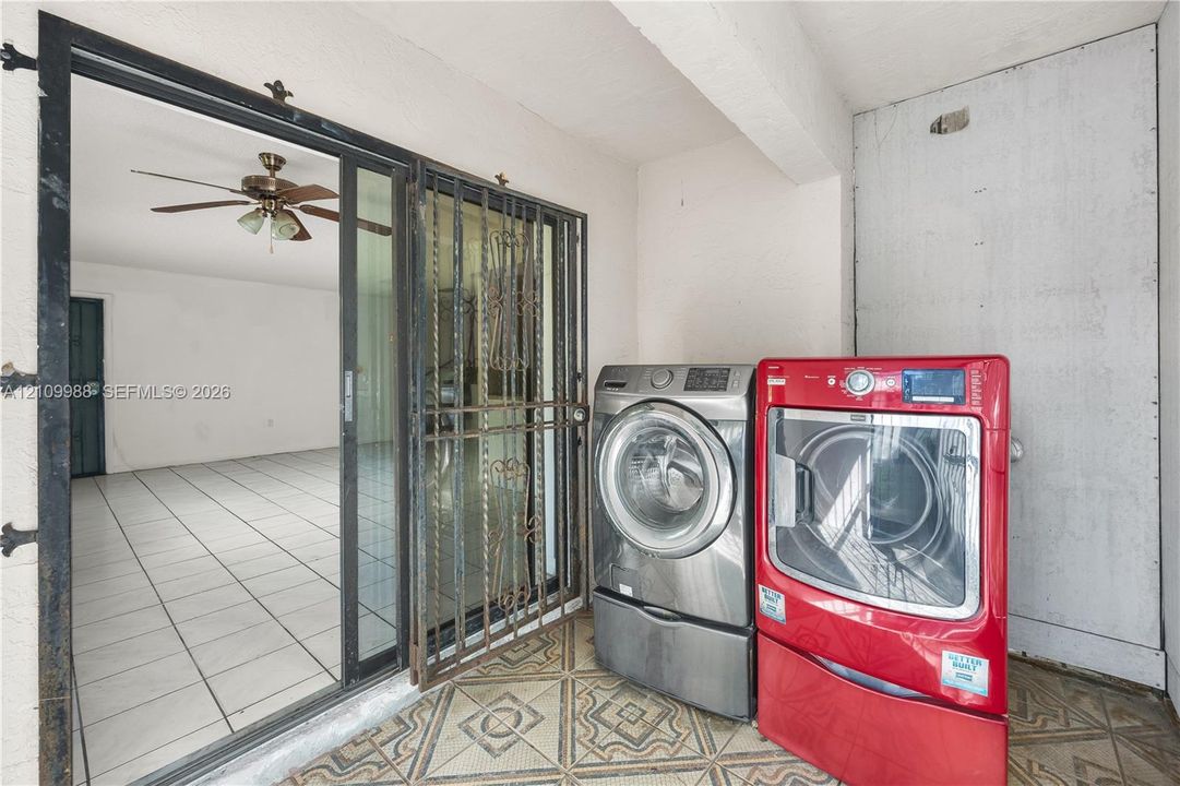 Covered patio featuring patterned tile flooring, a metal security screen door, and a sliding glass door