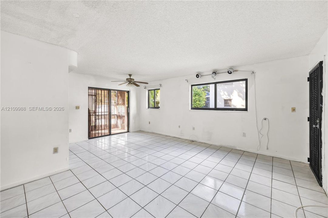Interior space featuring large-format ceramic tile flooring, a multi-blade ceiling fan, metal security door, and sliding glass patio door