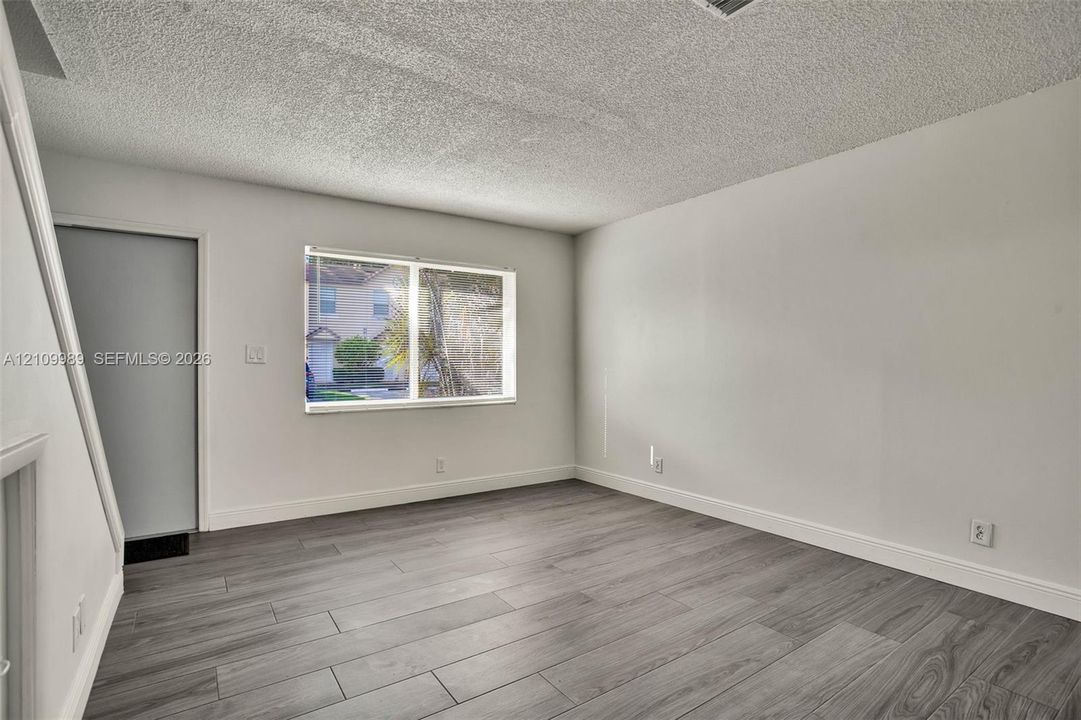 Neutral interior space featuring wood-finish tile flooring, neutral wall paint, and a rectangular window
