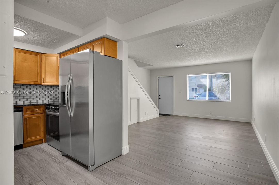 Kitchen featuring wood cabinetry, stainless steel appliances, and a tile backsplash, finished with wood-finish flooring