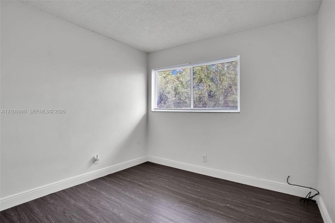 Interior room featuring wood-finish flooring, a horizontal sliding window, and textured ceiling finish