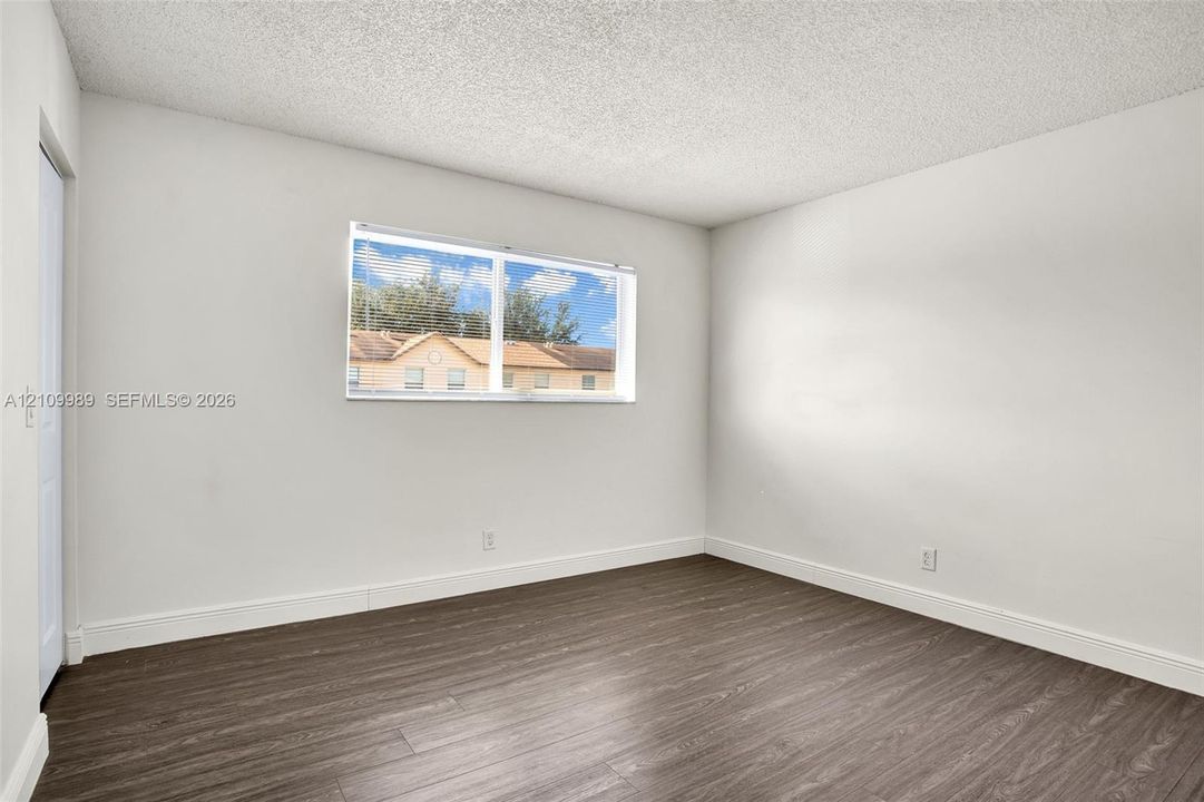 Neutral interior room featuring wood-finish flooring, white walls, and a horizontal window