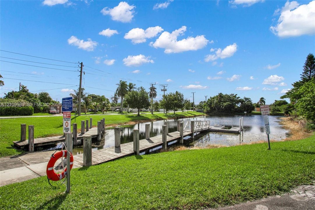 Waterfront property featuring a wooden boat dock, concrete piling supports, and manicured green space
