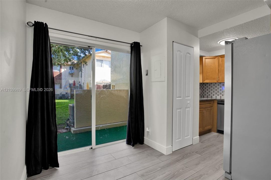 Sliding glass door, wood-finish flooring, built-in cabinetry, tiled backsplash, and stainless steel kitchen appliances