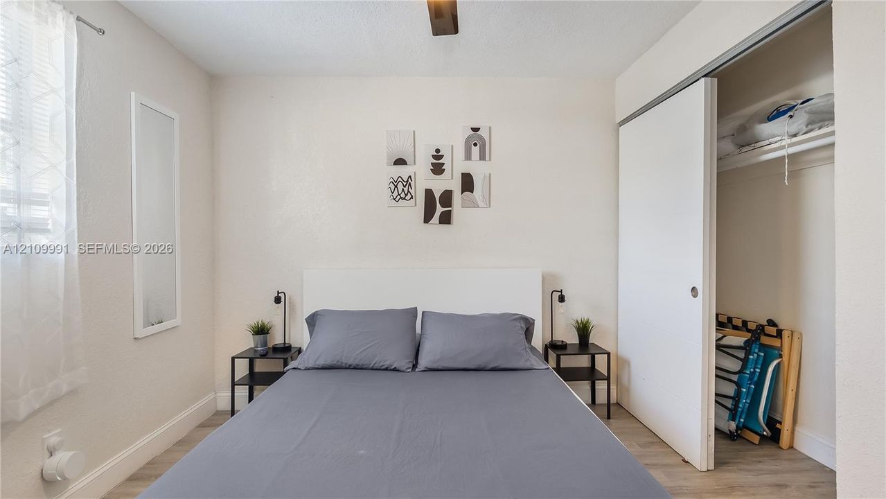 Neutral-toned room with wood-finish flooring, sliding closet door, and ceiling fan