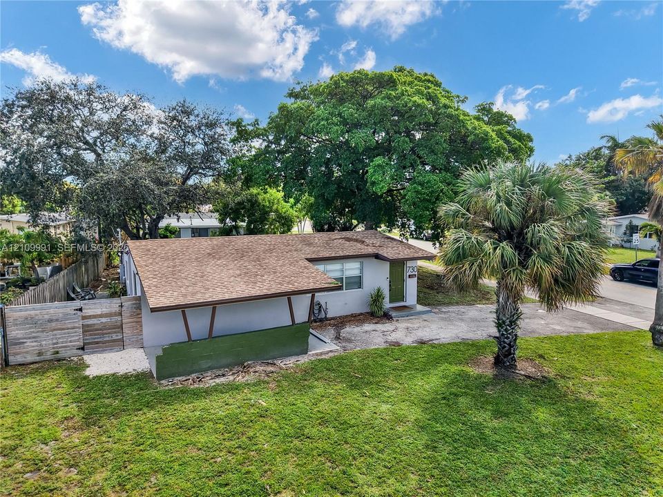 Single-story residence featuring an asphalt shingle roof, a carport with angled structural supports, mature landscaping, and a wood privacy fence