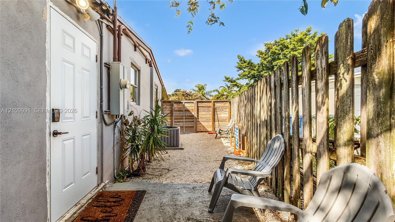 Exterior space featuring a concrete patio, gravel ground cover, and enclosed wood privacy fencing
