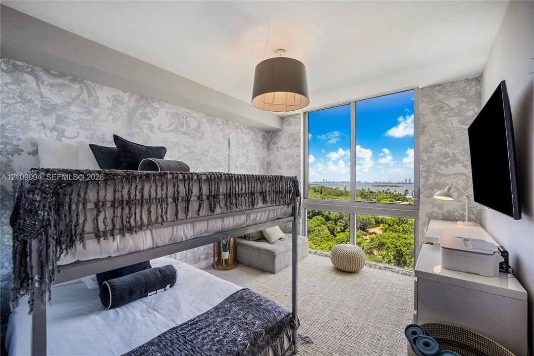 Floor-to-ceiling windows, panoramic coastal scenery, patterned wall coverings, drum-style ceiling light fixture, and neutral-toned wall-to-wall carpeting
