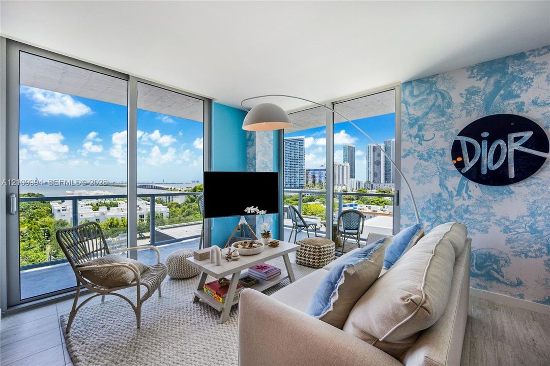 Floor-to-ceiling windows, wrap-around balcony with glass railings, and neutral tile flooring