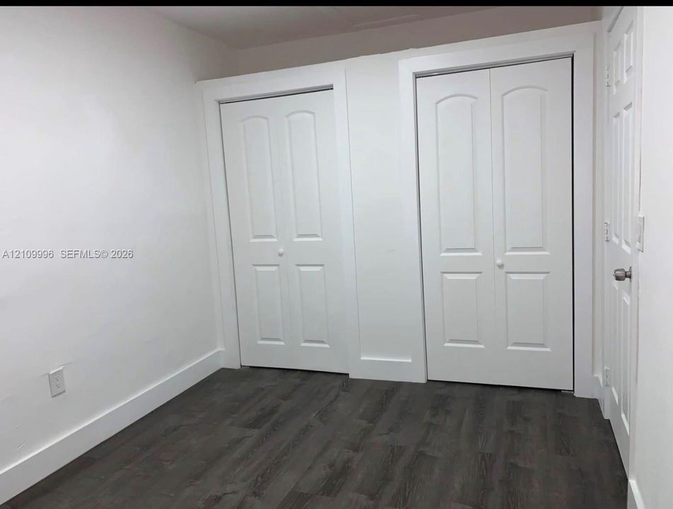 Wood-finish flooring, two sets of white paneled closet doors, and solid-core interior doors