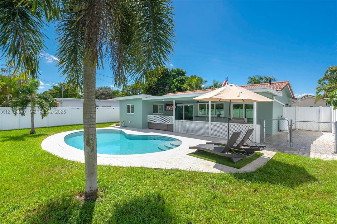 Backyard featuring an inground swimming pool, paver patio, vinyl privacy fencing, and exterior lattice screening