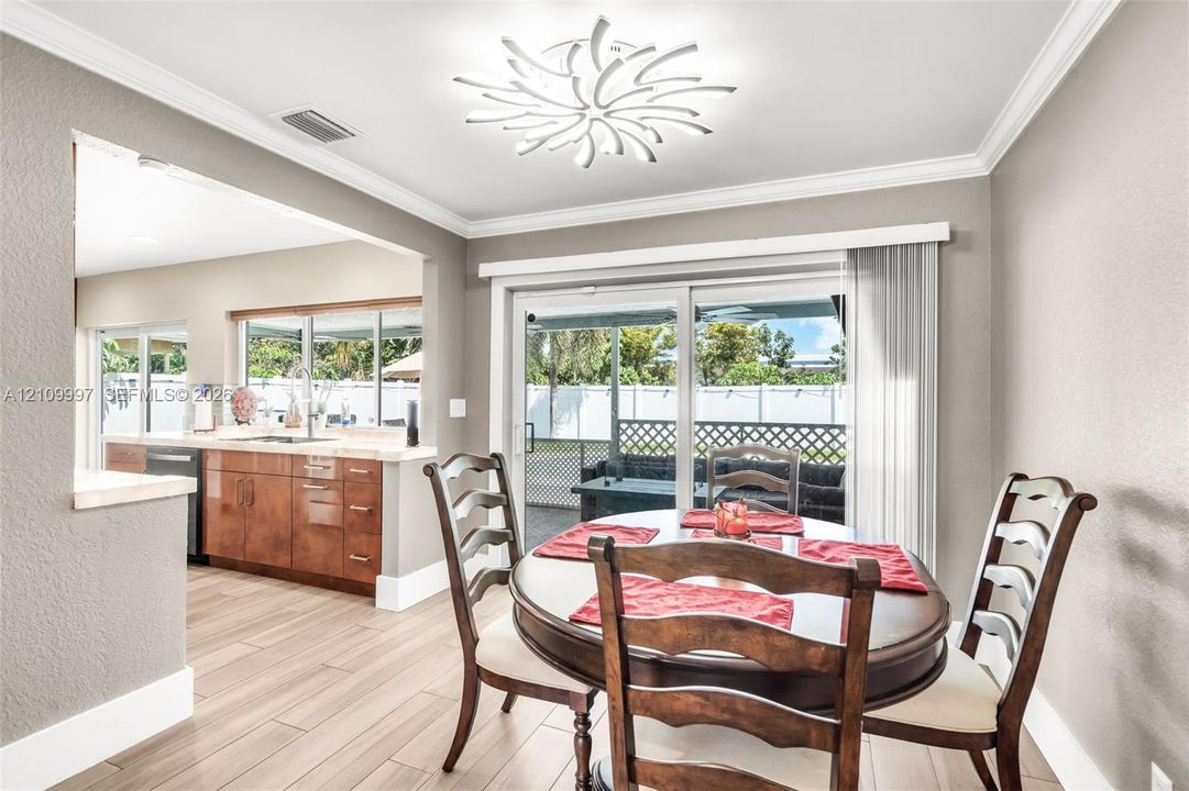 Dining area featuring wood-finish flooring, a decorative contemporary ceiling light fixture, and glass sliding doors providing exterior access