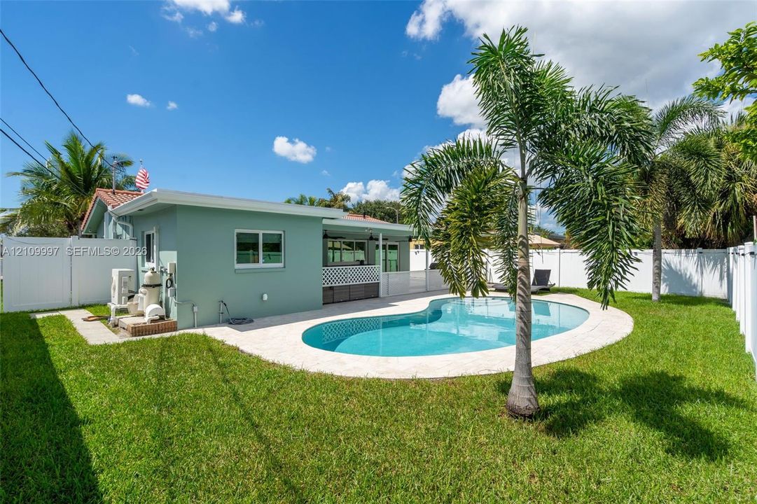 Backyard featuring a swimming pool, stone paver patio, covered porch area, and white vinyl privacy fencing