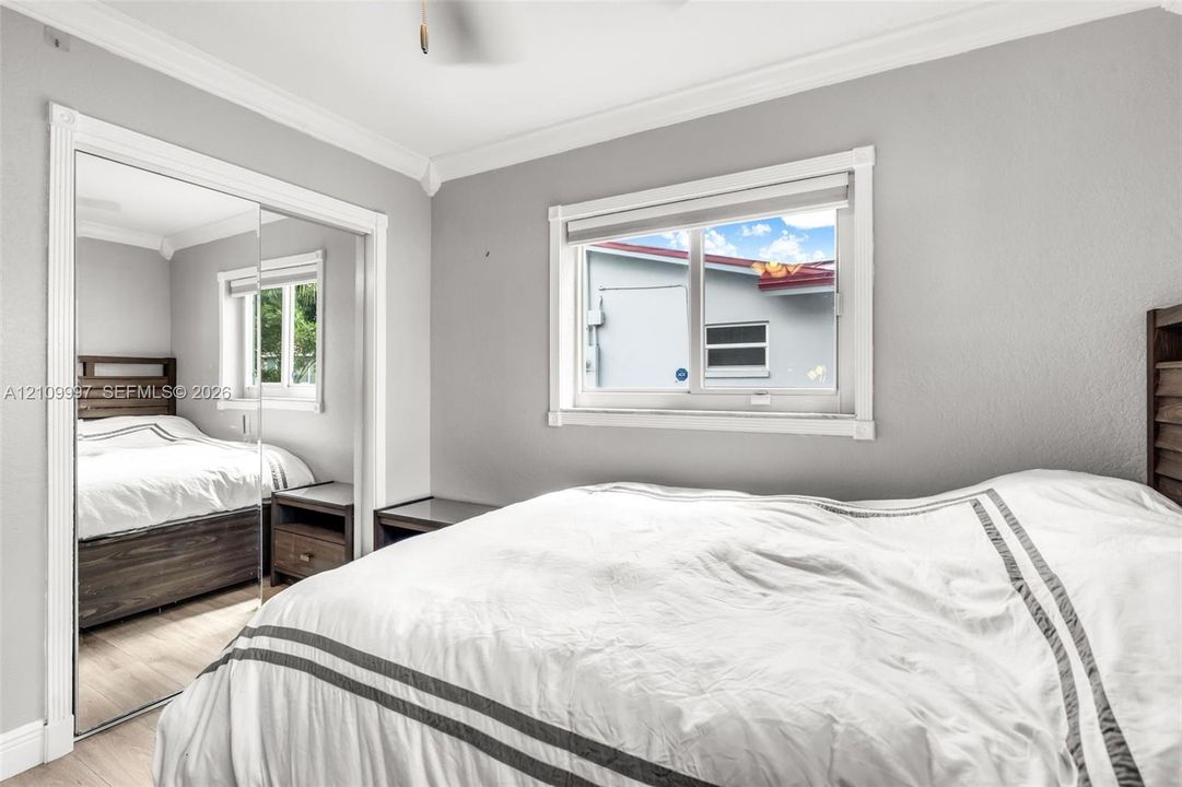 Room featuring neutral paint, crown molding, wood-finish flooring, and a sliding mirrored closet door