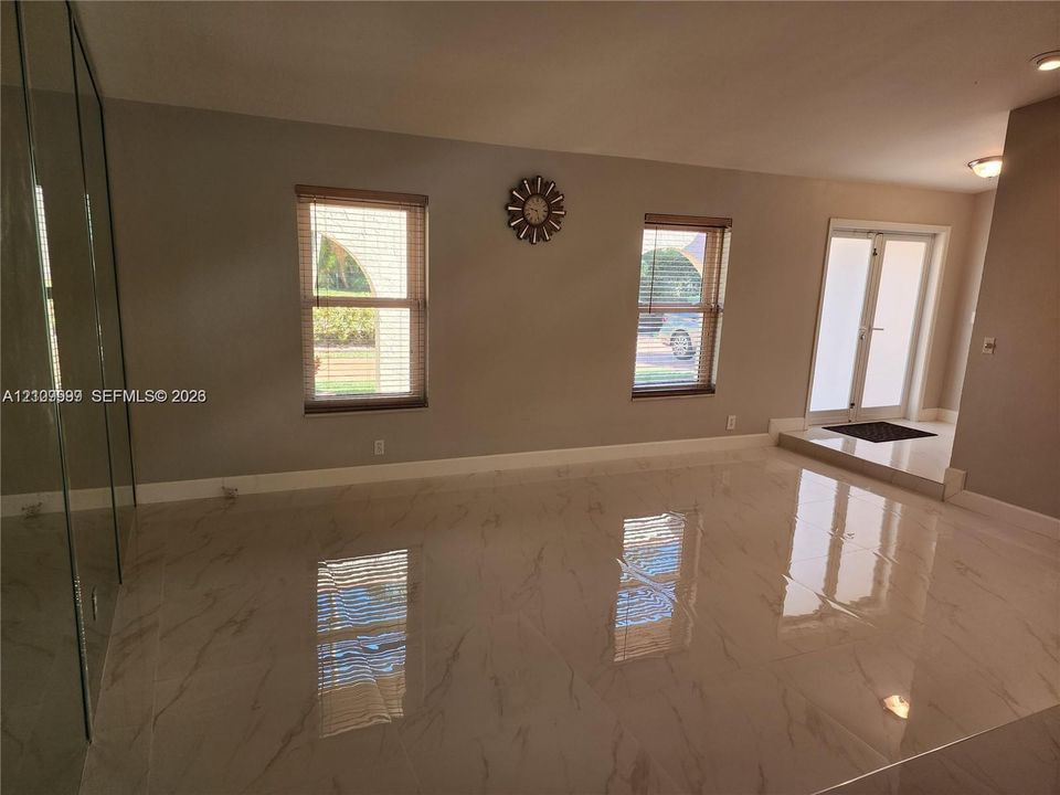 Large-format polished tile flooring, full-height mirrored wall, double-entry glass paneled doors, and dual windows