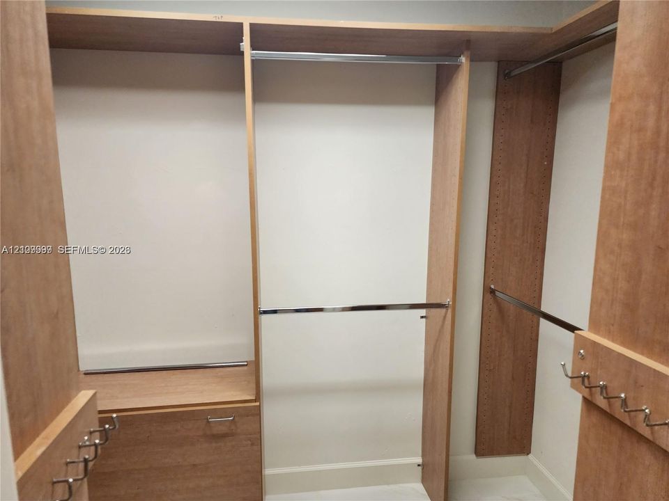 Custom wood-finish shelving unit featuring tiered hanging rods, built-in cabinetry, and integrated metal hooks
