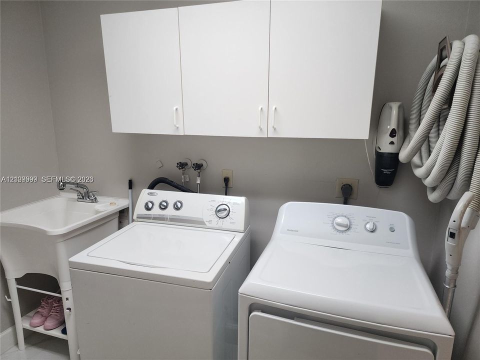Utility room featuring white cabinetry, a freestanding basin with a chrome faucet, and integrated laundry hookups