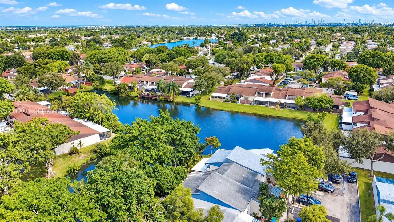 Aerial perspective featuring waterfront placement, mature tree canopy, and dense surrounding residential landscaping